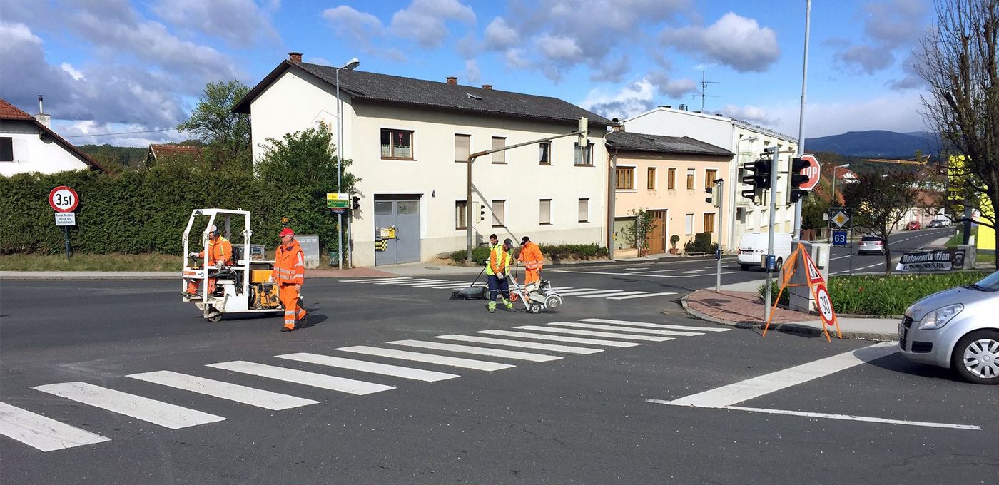 Foto: Straßenkreuzung in dörflicher Umgebung mit Arbeitern und Baugeräten