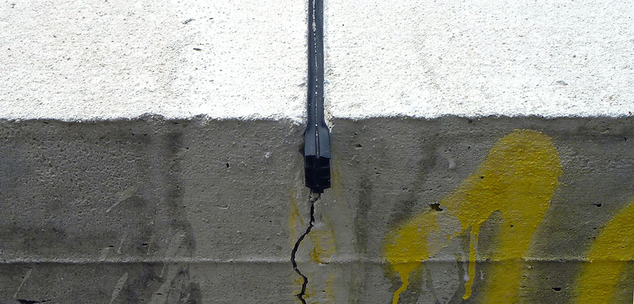 Foto: Nahaufnahme einer Betonplatte, in die eine Sollbruchstelle geschnitten wurde, die mit schwarzem Füllmaterial verschlossen ist